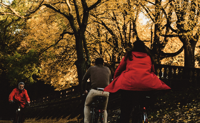 People biking through park with autumn foliage near CORE Rego NYC, new luxury apartments for rent in Rego Park.