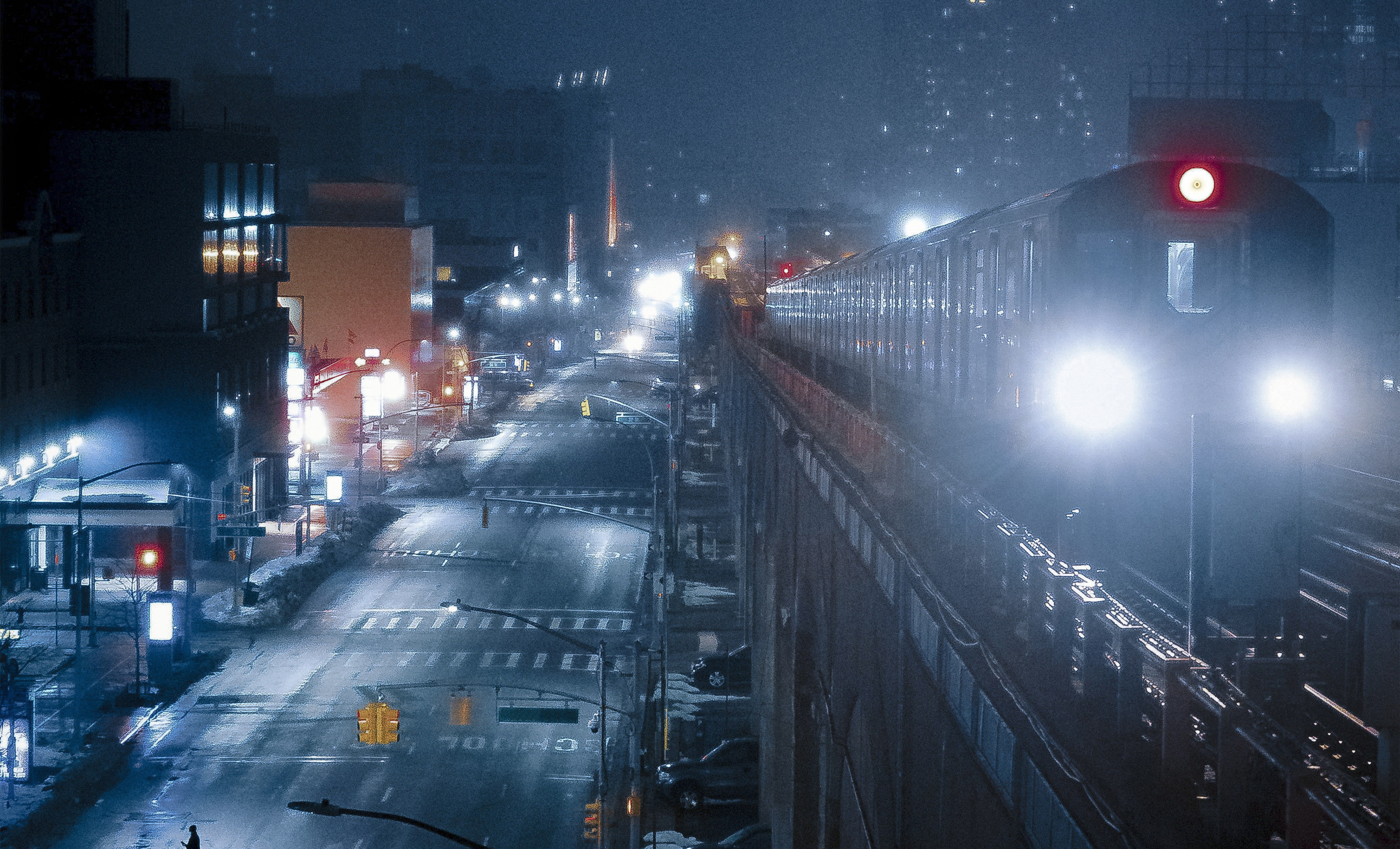 Night view of above-ground train passing by in Queens, NY near CORE Rego Park apartments.